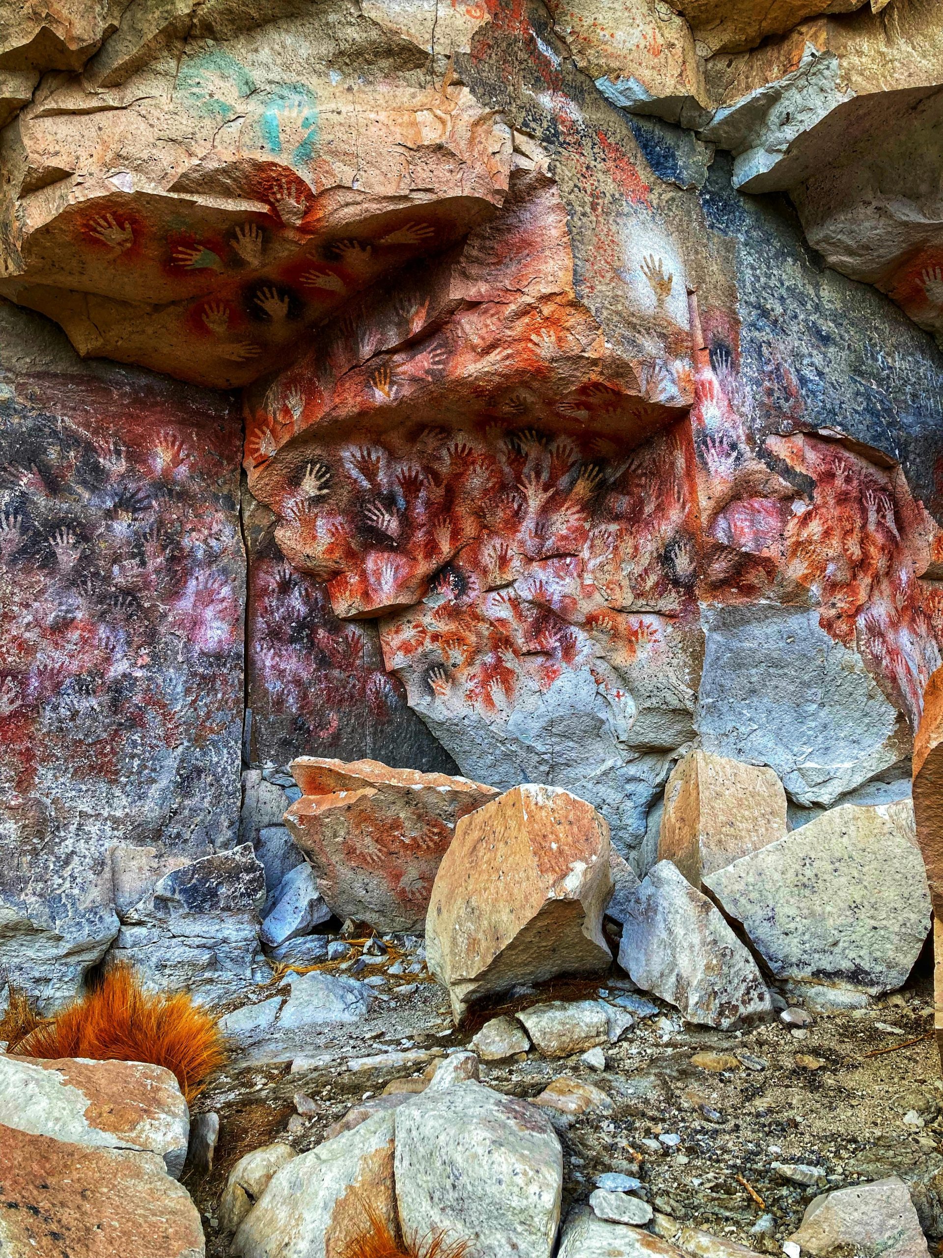Ancient cave paintings featuring handprints in various colors on the rock walls, likely created by early humans.
